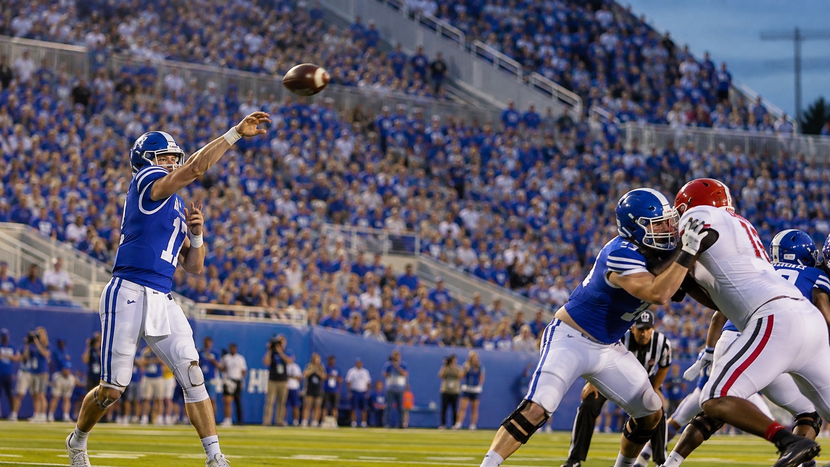 A generic college quarterback in blue throwing during a football game