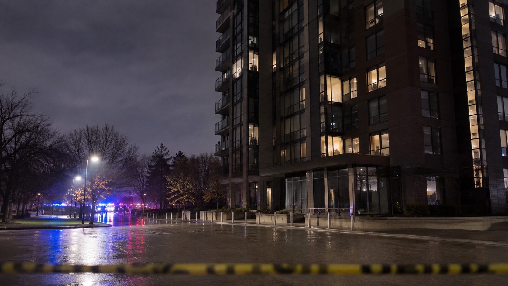 A generic downtown apartment building at night with distant emergency lights